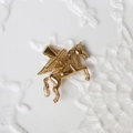 Macro shot of 18K gold plated Pegasus pendant with detailed wings on white surface - G12-3D Unicorn/Pegasus