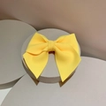 Detail of bright yellow bow hair clip with ribbed texture on a gray display stand - Hair Clip / Yellow