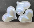Macro detail of three pearlescent iridescent heart-shaped DIY resin craft beads - 16x22mm / Iridescent White