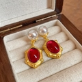 Detail of gold earrings featuring elegant white pearls and red oval gemstones on beige lining - 12# S925 Silver Pin Pearl Resin Oval Studs
