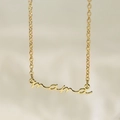 Close-up of a gold-plated necklace with a cursive Mama script pendant on a soft background - Gold