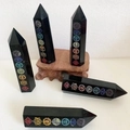 Set mit 5 schwarzen Obsidian-Chakra-Türmen mit bunten Symbolen und Holzständern - Sieben Chakra Symbole / 8-9cm