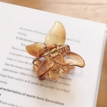 Amber flower hair claw clip in polished acrylic finish on a vintage book page - Amber