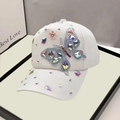 Detail of white baseball cap featuring colorful butterfly rhinestones and pink floral accents - Adult, Adjustable / White
