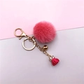 Detail of pink faux fur pompom keychain with golden bell and tassel pendant accessory - Rose Red