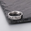 Primer plano de un anillo de acero inoxidable 316L con textura irregular sobre piedra - US 12 / Color Acero