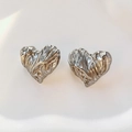 Macro shot of silver heart studs with unique lava texture and polished metallic finish - Earrings / Silver
