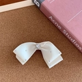 Détail d'une barrette à nœud en soie blanche ornée de strass et d'un cristal en cœur - Blanc