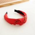 Close-up of red satin knotted headband featuring sparkling rhinestone embellishments - Red