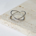 Detailaufnahme eines silbernen verschlungenen Doppelrings auf einer Travertinsteinplatte - US 6 / Silber