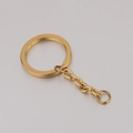 Vista macro de anillo plano dorado de 25mm en acero pulido con cadena de extensión para llave - Dorado