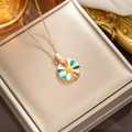 Golden titanium steel necklace with a rainbow colored flower pendant on a beige jewelry box - 309 Golden Drops Colored Daisy
