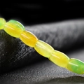 Polished yellow-green chalcedony beads on a textured dark grey background for DIY jewelry - Yellow Plus Green