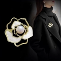 Detail of camellia brooch with white petals, gold trim and pearl on black background - White Camellia Gold Edge