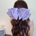 Eleganter lila Satin-Schleifen-Haarclip mit Perlen auf langem lockigem Haar gezeigt - Lavendel Lila Perle Schleife Federclip