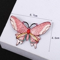 Enamel butterfly brooch with pink rhinestones and pearls on a white display stand - Pink
