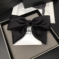 Close-up of black satin oversized bow hair clip in premium branded gift packaging box - Satin Bow / Black