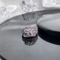 Close-up of silver ring featuring pink oval gemstones and bow design on black reflective surface - Style 5 Adjustable Ring