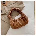 Close-up of brown ruched cloud handbag featuring soft faux leather pleats and texture - Brown