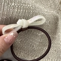 Gros plan d'un chouchou à nœud en acétate blanc nacré avec un élastique marron souple - Nœud en Acétate-Blanc