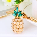 Golden pineapple keychain with champagne beads and green crystals for luxury handbags - White Cat Eye Pineapple