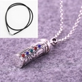 Detailed close-up of a silver cylinder pendant with colorful stones on a gray felt background - Pendant with Leather Cord