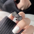 Close-up of black oil-dripped butterfly ring with pavé zircon crystals on a model hand - Black Simple Pave Bowknot