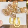 Vista macro di elastici per capelli con fiocchi in resina glitterata su cartoncino - Giallo
