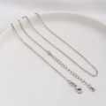Detailed macro view of a silver flat O-chain necklace with a lobster clasp and waterdrop charm - Flat Cable Chain / White Gold