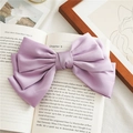 Détail d'une pince à cheveux en satin lavande multicouche sur un livre ancien - Violet