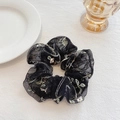 Chouchou élégant en résille noire avec broderie florale sur une surface en lin blanc - Chouchou à Paillettes Noires