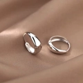 Dettaglio macro di orecchini a goccia in argento su sfondo di seta color kaki - Stile Rotondo / Argento