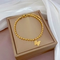 Détail macro d'un bracelet en acier titane rose doré avec pendentif papillon givré - Doré