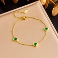 Detail van een gouden roestvrijstalen armband met drie groene hartvormige edelstenen - Hart Charm Armband (B1253)