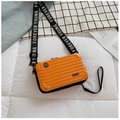Macro shot of orange hardshell suitcase crossbody bag with textured stripes and logo strap - Orange