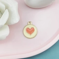 Detail eines orangen Emaille-Herzanhängers mit gewelltem Goldrand auf Rosa Tablett - Weiß Rosa Herz