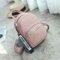 Mini mochila de cuero PU rosa con pompón gris y asa superior sobre un fondo texturizado - Con bola de pelo / Rosa