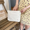 White corduroy cosmetic pouch detail with distinct vertical texture and branded label - Milk White