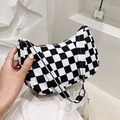 Detail of black and white checkerboard canvas shoulder bag held against a white wall - Black and White Plaid