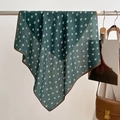 Close-up of green silk scarf featuring white leaf patterns and brown hem on a metal bar - 68*68cm / Dark Green