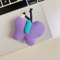 Detailansicht eines lila Plüsch-Schmetterlings mit grüner Mitte auf einem Laptop - Schmetterling / Lila