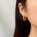 Minimalistische dicke goldene C-Form Creolen getragen von einem Modell im Profil - Gold