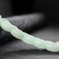 Polished light green oval jade beads on a textured grey background for DIY jewelry - Light Green