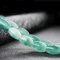 Detailed close-up of oval green jade beads showing natural textures and luster - Cyan Marbled