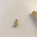 Colgante de oso bañado en oro con micro pavé de circonitas sobre un fondo minimalista - Oso Dorado con Microengaste de Circonita