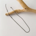 Close-up of a silver-tone flat snake chain necklace draped over a natural wood branch - Silver Titanium Steel Blade Chain