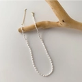 Minimalist white pearl necklace with gold lobster clasp hanging on a wooden branch - Matte Pearl Necklace