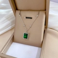 Macro-opname van zilveren kralenketting met smaragdgroene steen in beige doosje - Titaniumstaal / Zilver