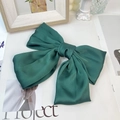 Detail shot of the large dark green satin bow hair clip with a silky texture on a table - Dark Green (Spring Clip)