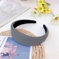 Detailed view of houndstooth headband on a rustic straw mat with elegant floral accents - Small Grid